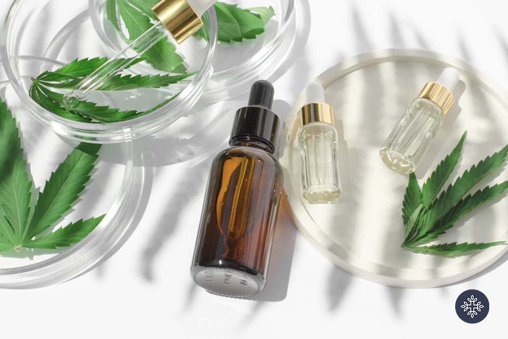 A half-filled unlabeled glass bottle laying beside hemp leaves and mini glass bottles