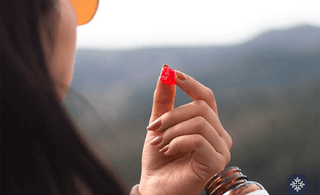 A woman on a mountain taking a CBD gummy