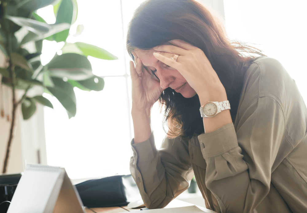 Woman experiencing migraine, massaging her forehead with both of her hands
