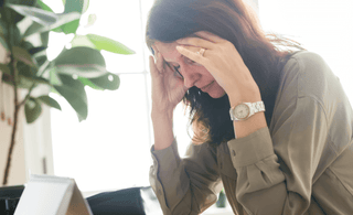 Woman experiencing migraine, massaging her forehead with both of her hands
