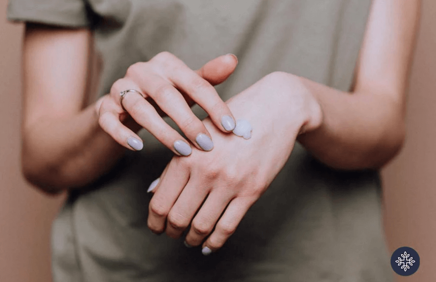 Photo of woman applying CBD lotion on the top of her hand. 