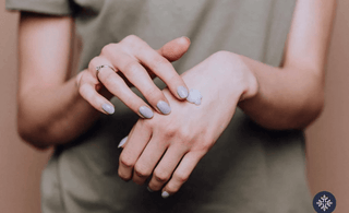 Photo of woman applying CBD lotion on the top of her hand. 