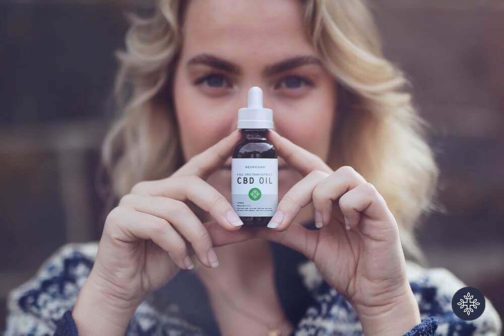 A woman holding a bottle of Neurogan CBD Oil 