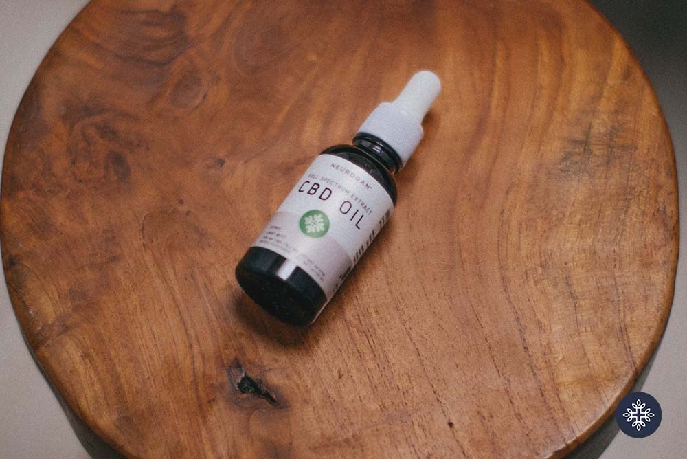 Neurogan CBD Oil laying on a round wooden tab