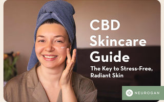 A smiling woman with hair towel, applying CBD cream on her face.