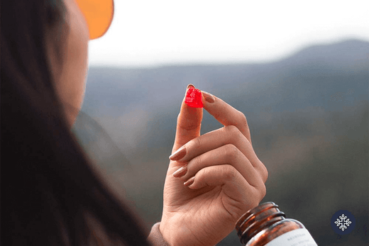 A woman on a mountain taking a CBD gummy