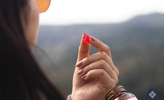 A woman holding a piece of red CBD Gummy Squares, mountain range in the background
