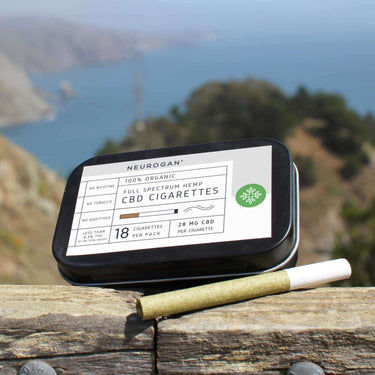 A CBD cigarette beside the pack, in a relaxing mountain and coast scenery