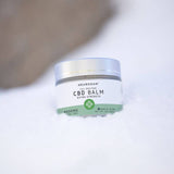 Jar of CBD Muscle Balm in 2oz (60ml) container, placed on a snowy surface