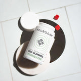 An open bottle of CBD gummies laying on a tile surface, with two gummies outside the bottle.