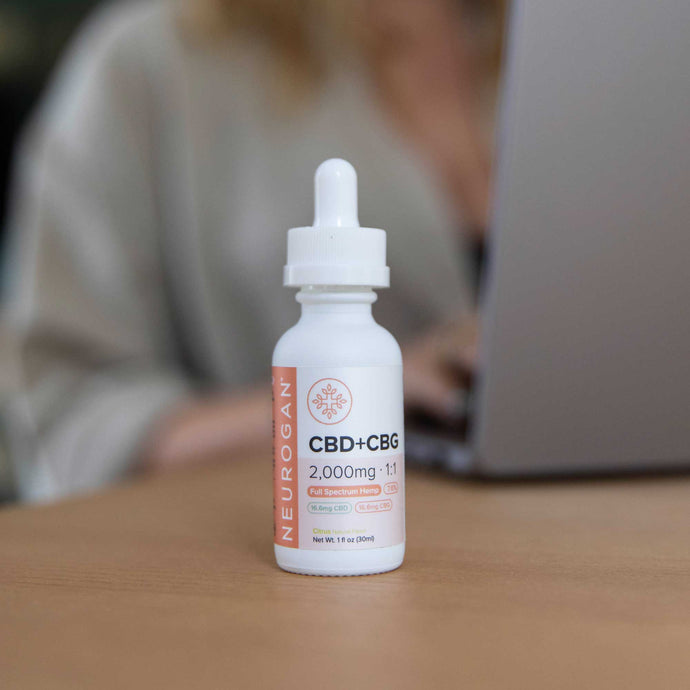 CBD+CBG Oil 2000mg on a desk next to a woman typing