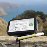 A CBD cigarette beside the pack, in a relaxing mountain and coast scenery