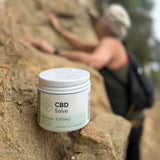 Elder woman on a hike and CBD Salve standing on a rock