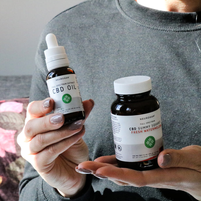 A woman holding bottles of Full Spectrum CBD Oil and CBD gummies