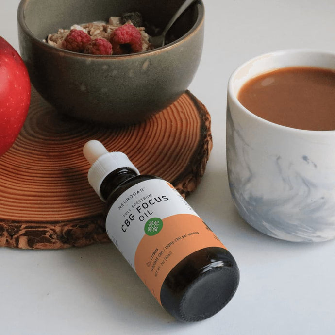 CBG Focus oil on a table with a breakfast meal of apple, fruity oatmeal, and coffee