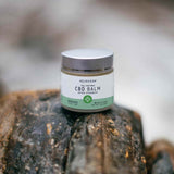 CBD Balm on a rocky surface beside a river