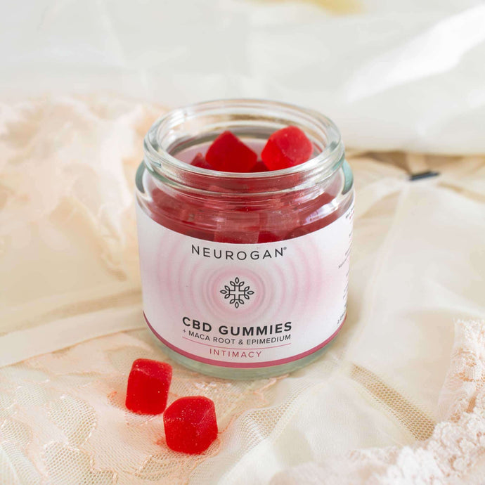 An open bottle of CBD gummies for sex laying on a white lingerie