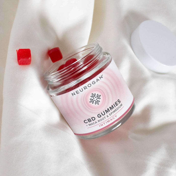An open bottle of CBD gummies for sex laying on a white bed linen