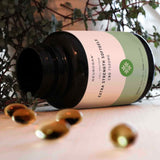 An open bottle of CBD extra strength softgels with five softgels outside the bottle.