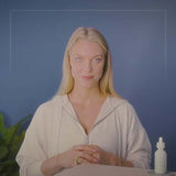 Young woman showcasing a CBD tincture bottle against a blue background, promoting natural wellness.