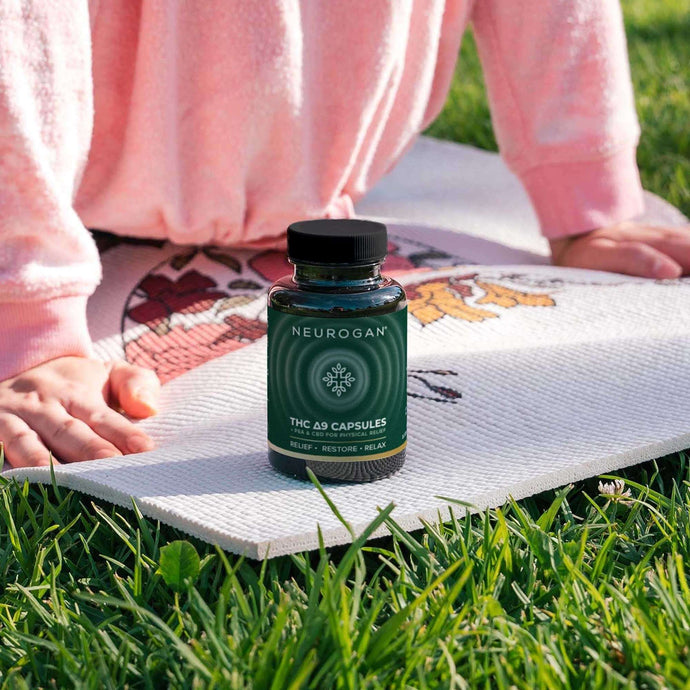 Bottle of THC capsules placed on a mat beside a woman doing a yoga exercise