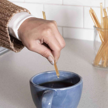 hand pouring the content of CBD Honey sticks into a mug
