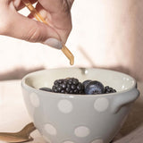 Person adding CBD Honey Stick on a bowl of mixed fruits