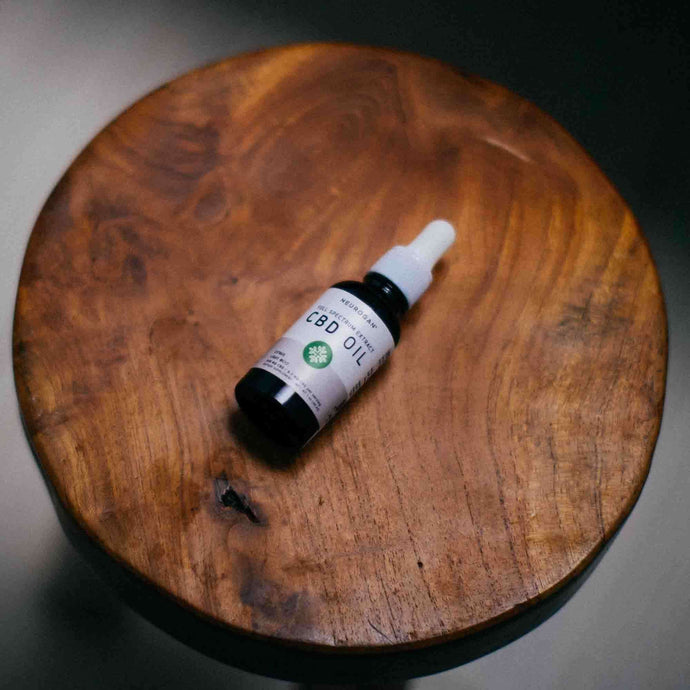 Bottle of CBD oil on a round wooden plank