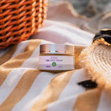 Neurogan CBD face cream on beach towel beside a summer hat and a wooden basket