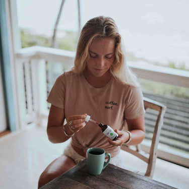A woman preparing her dose of CBD oil and infuse into of a cup of drink
