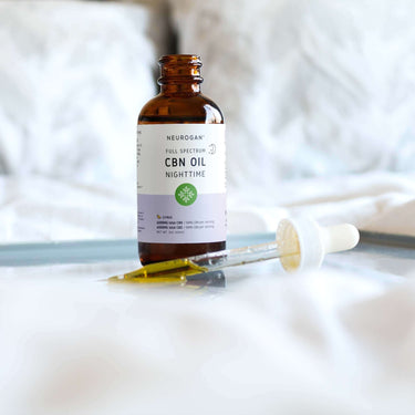 An open CBN Bottle and a half-filled dropper on a white bed