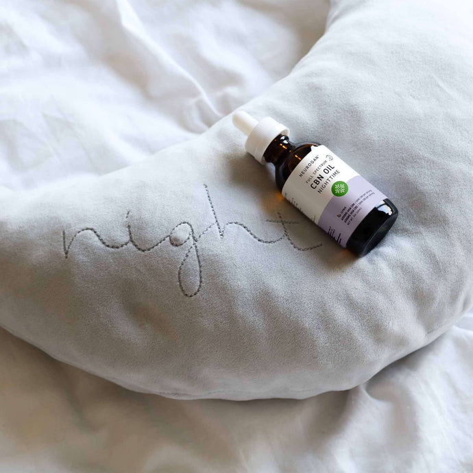 Full Spectrum CBN Oil bottle laying on a pillow with "night" embroidered