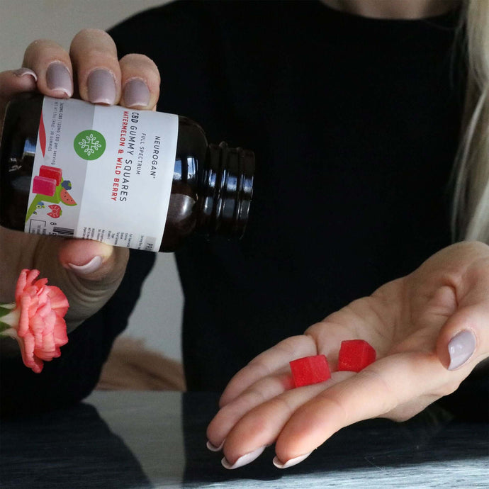 woman dropping two pieces of Red CBD Gummy squares onto her hand