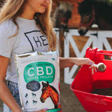 woman holding a food scooper and bag of Neurogan Full Spectrum CBD Horse Pellets