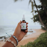 Handheld bottle of 500mg citrus CBD oil on a beach scenery