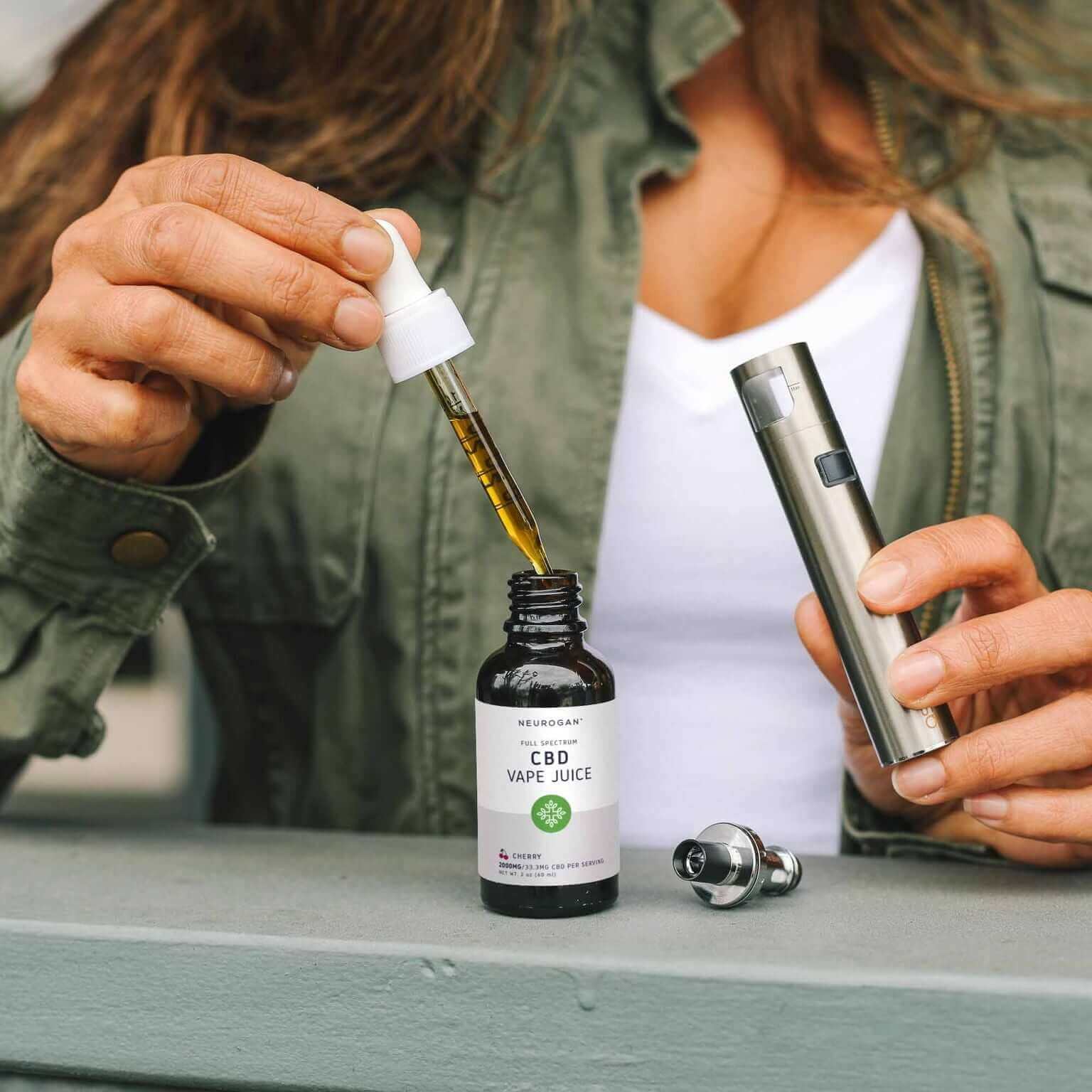 Woman filling up the dropper of CBD vape juice from the bottle